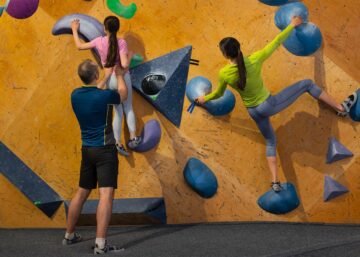 Familia formada por padre, madre e hija practicando escalada indoor en un centro Climbat, ideal para iniciarse en la escalada en familia en un entorno seguro y adaptado.