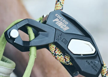 Dispositivo de aseguramiento PINCH de Edelrid fijado al arnés, mostrando su diseño compacto y ergonómico.