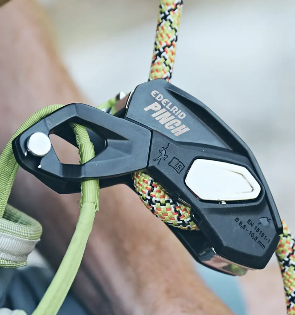 Dispositivo de aseguramiento PINCH de Edelrid fijado al arnés, mostrando su diseño compacto y ergonómico.