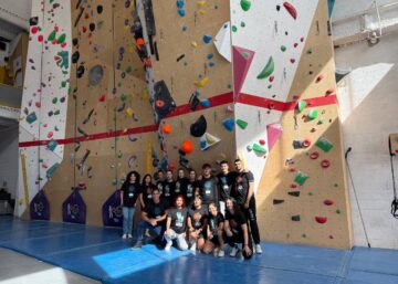 Grupo de empresa posando frente al muro de escalada tras una jornada de team building en Climbat.