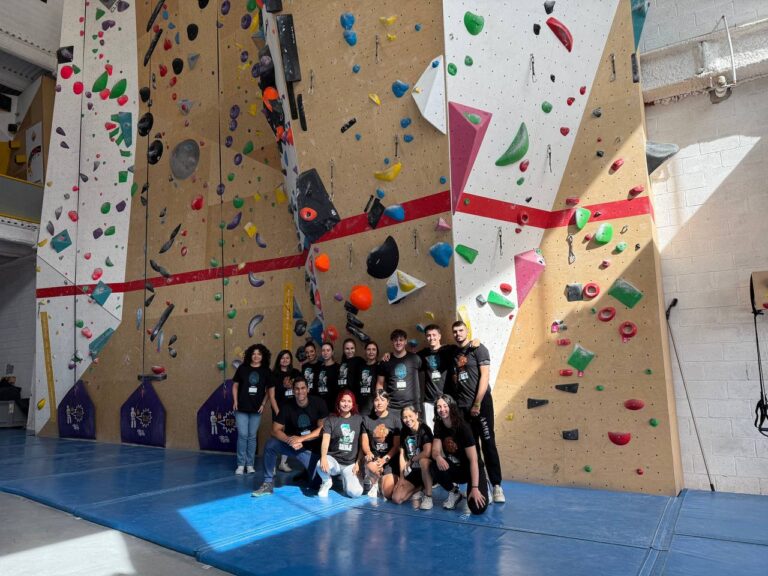 Grupo de empresa posando frente al muro de escalada tras una jornada de team building en Climbat.