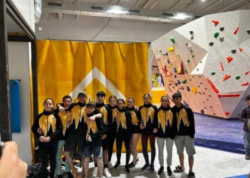 Equipo de tecnificación Climbat posando en un rocódromo indoor durante una competición de escalada en bloque.