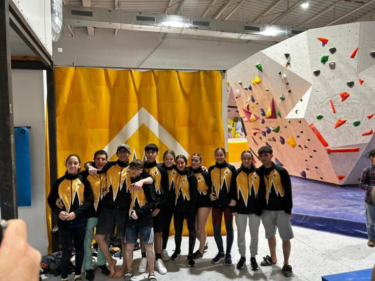 Equipo de tecnificación Climbat posando en un rocódromo indoor durante una competición de escalada en bloque.