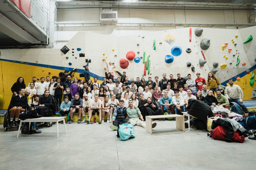 Grupo numeroso de participantes posando en un rocódromo durante un evento de escalada en bloque.