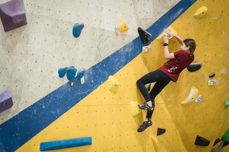 Niña participando en la liga infantil de escalada en un rocódromo Climbat